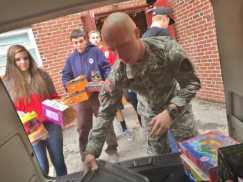 Wiscasset Middle High School sophomore Lindsey Gordon, followed by senior Alex Webber and junior Grant Hefler help Brandon Keene of Maine Army National Guard’s 133rd Engineering Battalion load gifts into a vehicle Dec. 18. SUSAN JOHNS/Wiscasset Newspaper