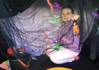 Natalie Sinclair, 7, of Wiscasset smiles behind a web-like mesh in a vehicle where she and her mother Amy Sinclair were giving out treats. SUSAN JOHNS/Wiscasset Newspaper
