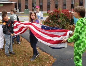 Preparing to retire the colors for the day are: Noah Ruzyckij, Gabby Dodson and Garrett Marshall. Madelynne Richardson is shown in the background. PHIL DI VECE/Wiscasset Newspaper