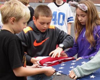 Carefully folding the American flag into a triangle are, from left, Wiscasset Elementary School fifth graders Alex Akers, Noah Ruzyckij and Gabby Dodson. PHIL DI VECE/Wiscasset Newspaper