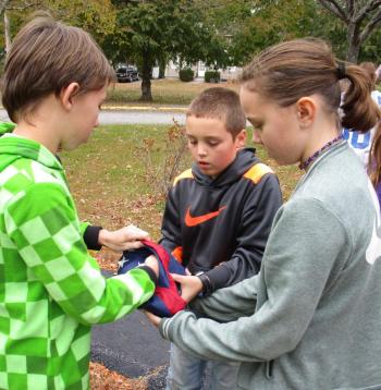 Garrett Marshall, Noah Ruzyckij and Kasey Pinkham finish folding the flag by tucking its corner inside. PHIL DI VECE/Wiscasset Newspaper