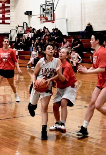 Kailee Colby drives to the basket. Defending is alumna Bella Orr. At left, Lindsey Gordon and Brianna Goud. PHIL DI VECE/Wiscasset Newspaper