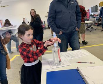 Grace Walker, 6, uses the hand sanitizer following town meeting. SUSAN JOHNS/Wiscasset Newspaper