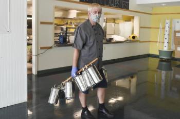 Chef Mikael Andersson collecting LA’s new tiffin boxes after lunch. He uses an old broomstick to collect the tiffins from classrooms, a technique he refers to with a laugh as “old world technology.” Courtesy photo