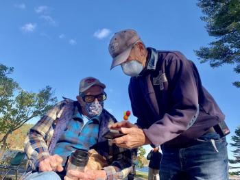 George Richardson, seated, and Paul Bunyon look at something on a phone before the ceremony. SUSAN JOHNS/Wiscasset Newspaper