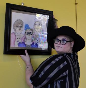 Art from the Heart Co-Chair Marguerite Eastman hangs her portrait " Love is Love" at the ClC YMCA. Gallery in Damariscotta. Ellie Busby photo