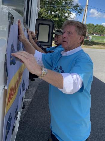 Maine Sen. Bill Diamond, D – Windham, foreground, and Rep. Jeff Hanley, R – Pittston, put a poster on a camper at Wiscasset Community Center Wednesday afternoon, Sept. 29, for a stop on Diamond’s “Walk a mile in their shoes tour” promoting child protective services reform and honoring Wiscasset’s Kendall Chick and other slain children. SUSAN JOHNS/Wiscasset Newspaper