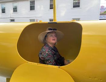 Newcastle’s Adrianne Zahner tries out a yellow submarine of sound at the June 30 Wiscasset Art Walk. SUSAN JOHNS/Wiscasset Newspaper