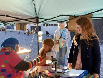 Her mom, Lisa Albert, and her friend, Jezreel Quist, watch as volunteer Ruth Burke creates a painting on Tessa Albert’s arm. EDNA MILLER/Wiscasset Newspaper Event