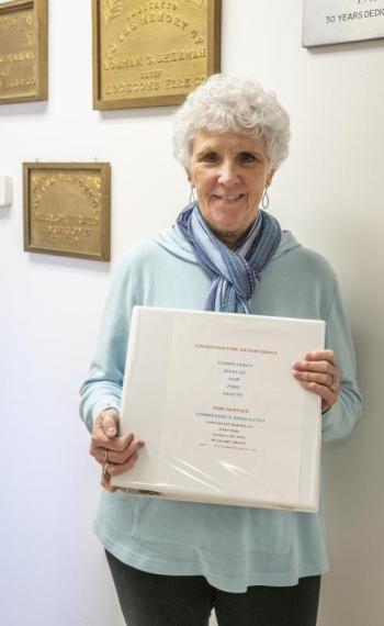 Lynn Martin poses with the manual she created for the Edgecomb Fire Department. Consulting with fire departments on safety issues has become a passion for Martin, whose previous career was primarily in the medical field. Bisi Cameron Yee photo Lynn Martin
