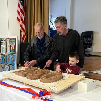 The present, past and future generations of Edgecomb cut the ceremonial cake at Edgecomb’s 400th birthday party March 17. From left, Willis Clifford, Mike Smith, and Reid Carver. FRITZ FREUDENBERGER/Boothbay Register