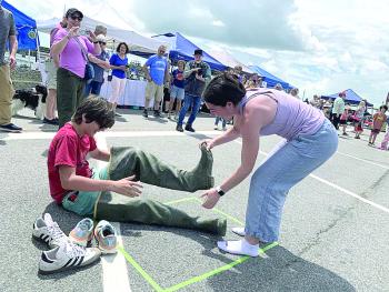 Eleanor Lynch helps cousin Owen O’Toole off with the waders in a relay at Wormfest in Wiscasset June 8. SUSAN JOHNS/Wiscasset Newspaper 