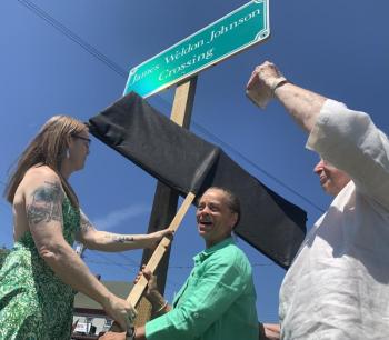 From left, Heather Jones and State Sen. Rachel Talbot Ross unveil one of the new signs naming the Main Street, Wiscasset railroad crossing James Weldon Johnson Crossing, as Terry Heller holds a phone on which Johnson’s great niece Melanie Edwards and Tony Hill, past lawmaker in Johnson’s native Florida, attend via Zoom June 26. SUSAN JOHNS/Wiscasset Newspaper Ceremony