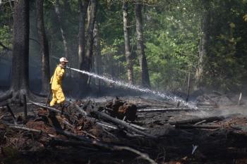 A firefighter sprays hotspots in Waldoboro, Aug. 9, 2025, during a brush fire. Two days later, Aug. 11, St. George firefighters extinguished an approximate 30' x 30' brush fire on inner edge of a quarry off River Road. (Photo by Sarah Thompson)