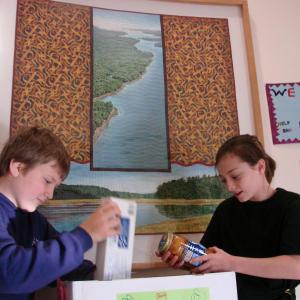 Alex Hibbard, left, and Emily Harris check out some of the donations their class at Edgecomb Eddy School has collected so far for the Boothbay Region Food Pantry. SUSAN JOHNS/Wiscasset Newspaper