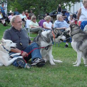 Georgetown's Ken Hoffman and his three adopted huskies, from left, Xena, from the Coastal Humane Society in Brunswick, and Bandit and Maximum, both from the Lincoln County Animal Shelter in Edgecomb, take in a Pan Fried Steel concert on the Wiscasset common August 22. Sometimes, the dogs sing along at concerts, Hoffman said. SUSAN JOHNS/Wiscasset Newspaper