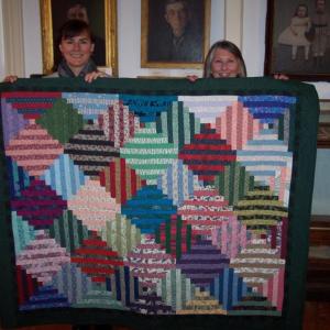 Boothbay Region Historical Society Office Manager Marnie Mitchell, left, and former Administrator Kathleen Duffy display a colorful handmade quilt, this year's raffle prize. Courtesy of Susan Lloyd