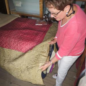 Quilt expert Faye Snyder examines an 18th century quilt from the Lincoln County Historical Association collection. See this and many other fine quilts at “Keeping Warm in Mid-Coast Maine, a Textile Symposium to be held on June 28 and 29. Courtesy of Christine Hopf-Lovette