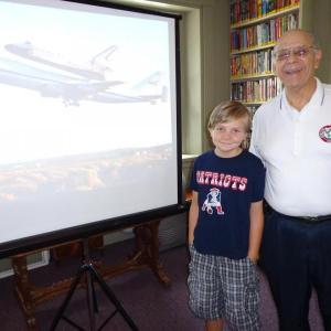 Jack Castonia and Ed Polewarczyk pose next to a space shuttle image after the Space Alliance presentation. Courtesy of Wiscasset Public Library