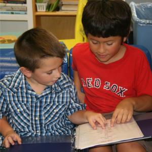 Kindergartner Trey Tibbetts reads a poem with help from his reading buddy, fourth grader Marcus Russano. Courtesy of Center for Teaching and Learning