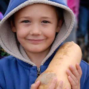 A young boy holds a squash grown at The Morris Farm. Courtesy of The Morris Farm