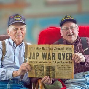 Howard Cederlund, left, of Wiscasset and George Hanna of Round Pond look through an old newspaper saved by Cederlund’s father-in-law announcing the end of World War II. Courtesy of Anne Cederlund