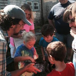 Morris Farm educator John Affleck holds a bowl of ice cubes with flowers inside them, during an Aug. 6 celebration of learning for the Wiscasset School Department’s summer program. Showing interest are Kylee Smith, 7, left, and Hunter Giroux, 6, both of Wiscasset. SUSAN JOHNS/Wiscasset Newspaper John Affleck, Morris Farm, Kylee Smith, Hunter Giroux