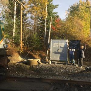Maine Eastern Railroad’s final passenger excursion run nears Old Ferry Road in Wiscasset Sunday afternoon as Gordon and Lynne Kontrath, neighbors of the tracks, wave and hold up a goodbye sign. SUSAN JOHNS/Wiscasset Newspaper