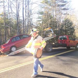Wiscasset Fire Chief T.J. Merry removes a cone from the scene of an accident on Foye Road Nove. 29, as Blagden’s Wrecker Service removes the car. SUSAN JOHNS/Wiscasset Newspaper