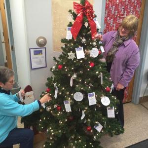 Wiscasset Selectmen’s VIce Chairman Judy Flanagan, left and Wiscasset Administrative Assistant Kathy Onorato place wish tags on a tree in the municipal building. SUSAN JOHNS/Wiscasset Newspaper