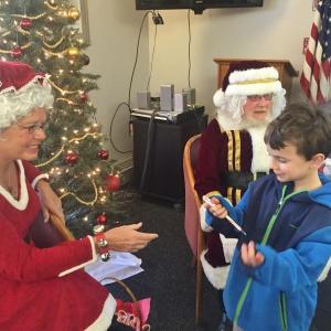 Kayden Reith, 6, of Dresden accepts a candy cane Dec. 19 at Wiscssset Community Center from Mrs. Claus, a.k.a., Mattie Welch of Jefferson as Santa Claus, a.k.a. Nim Welch motions for the next child in line to come forward. SUSAN JOHNS/Wiscasset Newspaper