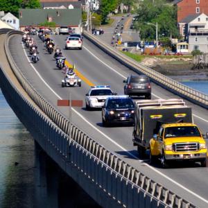 The Moving Wall, seen here being towed by the yellow truck, and motorcyclists cross the bridge from Wiscasset to Edgecomb. Courtesy of Kim Traina