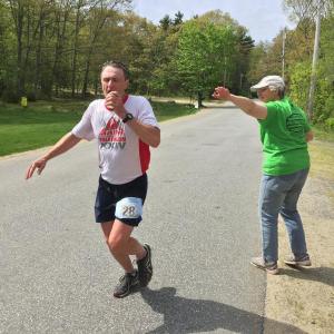 A runner gets some much needed water from a volunteer on Cross Point Road on Sunday, May 22. SUZI THAYER/Boothbay Register