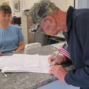 At the municipal building Monday, former selectman Bill Barnes signs off on his petition as Wiscasset Town Clerk Linda Perry looks on. PHIL DI VECE/Wiscasset Newspaper