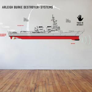 A schematic of an Arleigh Burke destroyer animates with the touch of a hand on the interactive exhibit wall, one of many high-tech elements featured in BIW: Building America’s Navy. Courtesy of Maine Maritime Museum