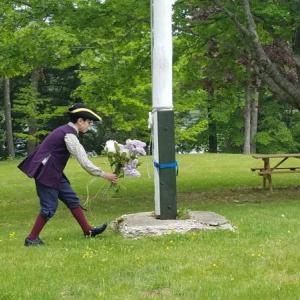 Young reenactor Joshua Kelley-Cohen, 9, places flowers at the base of the flagpole before the flag is hoisted to full at the Memorial Day ceremony in Dresden. KATRINA RICKERMANN/Wiscasset Newspaper