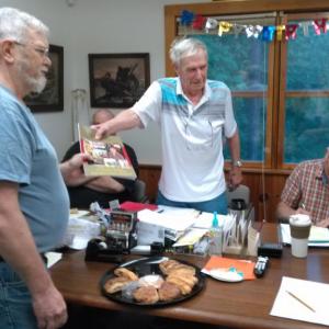 Retired fire chief Robert “Bob” Mooney, far left, receives the Westport Island town report dedicated to his service from Selectman George Richardson, center, at a surprise celebration June 11. JANE CARPENTER/Wiscasset Newspaper