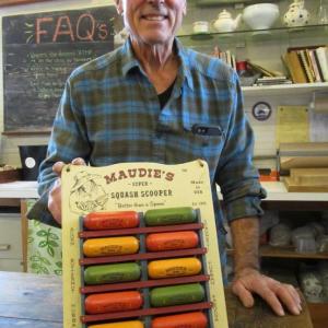 Art Weber poses in Treats on Main Street, Wiscasset with a display of his U.S.A.-made Maudie’s Super Squash Scoopers. PHIL DI VECE/Wiscasset Newspaper