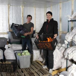 Twin Villages Foodbank Farm Farm Manager Sara Cawthon, right, and Assistant Manager Kaitlyn Gardner show off crates of fresh produce stored in the walk-in cooler at the farm’s new food storage hub. Courtesy photo