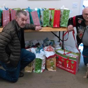 Reid Hodgdon, left, and Daren Graves, assisted by Cinnamon, with gift bags for veterans at the Boothbay Harbor Rotary clubhouse. JANE CARPENTER/Boothbay Register