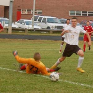 Logan Dupont negotiates the ball past the sliding effort of goalie L.J. Travis. ART MAYERS/Wiscasset Newspaper