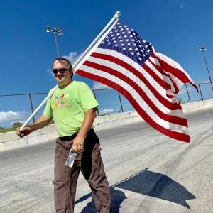 Merton Campbell carries Mike Warren’s flag around the track at Wiscasset Speedway Sept. 21, one of 21 laps Campbell made to help raise money for Dean Snell Cancer Foundation. SUSAN JOHNS/Wiscasset Newspaper