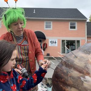 Damariscotta’s Deb Arter lets first-time Damariscotta Pumpkinfest attendee Evelyn Daniels-MacDonald, 5, of Richmond help with a giant pumpkin hedgehog in progress Friday, Oct. 11. SUSAN JOHNS/Wiscasset Newspaper