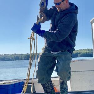 Terry Ashton holds onto the hoist as he moves from the deck of Top-Notch to a Wiscasset harbor dock Oct. 5. SUSAN JOHNS/Wiscasset Newspaper