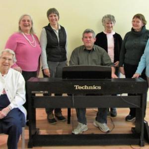 Gathered around accompanist Sean Fleming, music director of Hearts Ever Young, are the Troupe's new and returning members. Courtesy of Carol Teel