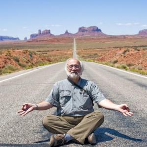 Bob Krist strikes a Buddha, or is it Jerry Garcia, pose to lighten the mood during a video shoot at Monument Valley. Courtesy of Bob Krist