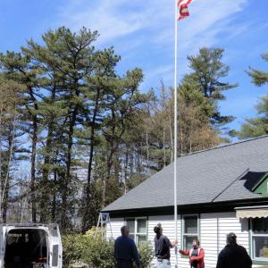 Jacob Carver, 10, right, foists the American flag at Westport Island’s town office. With him is Stephen Coombs; behind Coombs, Bill Miller. Courtesy of Gaye Wagner