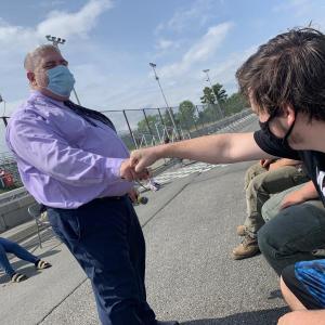 WMHS Principal Charles Lomonte and senior Kasey Mills bump fists at marching practice at Wiscasset Speedway June 9. Mills told Wiscasset Newspaper he was excited and happy for graduation. SUSAN JOHNS/Wiscasset Newspaper
