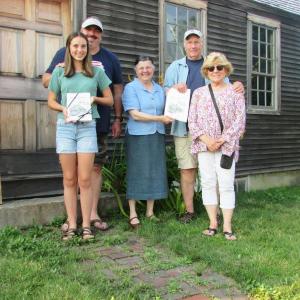Louise Miller, of the Chapman-Hall House Stewardship Committee, presents Sandi and Dan Day, their son Justin, and his daughter Zofie, with towels printed with Maurice “Jake” Day’s drawing of the Chapman-Hall House. Sons, Matthew and Darryl Day were not available for the photo. Photo taken in front of Chapman-Hall House. Courtesy of LCHA