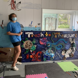 Juliet Fluty and the Trash to Treasure mural, made of collected trash such as bottle caps, ropes, buttons and plastic cutlery. LILLY CURTIS/Boothbay Register